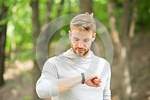 Sportsman training with pedometer gadget. Man athlete on busy face check fitness tracker, nature background. Athlete