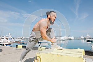 Sportsman with trendy hairstyle stretching body while standing at the sea pier