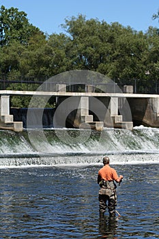 Sportsman in Waders Fishing at Dam