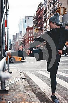 Sportsman warming up and stretching leg in urban streets