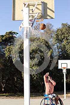 Sportsman in wheelchair throwing basketball into hoop