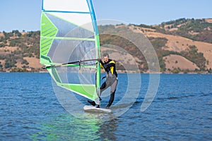 Professional windsurfer standing on board and holding sail. Space for copy