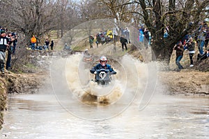 Sportsmen on BRP Can-Am quad bikes drive splashing in dirt and water at Mud Racing contest. ATV SSV motobike competitions are