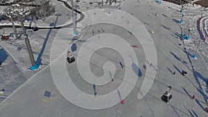 Sportsmen and tourists are skiing and snowboarding on slope of modern ski resort, aerial view