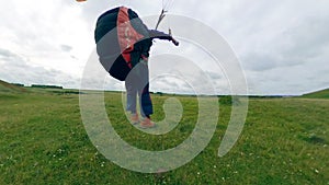 Sportsperson flying a paraglider, lands on a field.