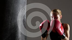 Sportswoman boxer knocks out of the punching bag. Slow motion