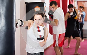 sportswoman in the boxing hall practicing boxing punches with boxing bag