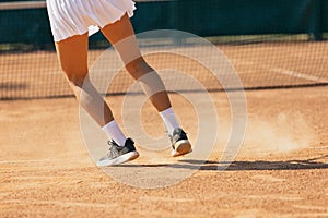 Sportswoman close-up legs in motion on tennis court