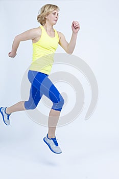 Sportswoman Concepts. Running Mature Sportswoman During Active Jogging Training Indoors Against White Background