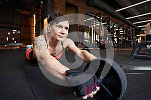 Sportswoman doing ab wheel rollout on gym floor
