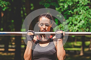 Sportswoman doing pullups in park.