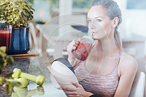 Sportswoman drinking healthy red cocktail
