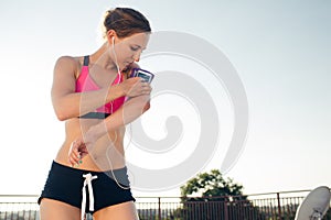 sportswoman in earphones using smartphone in running