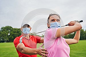 Sportswoman with a golf club over her head looking away