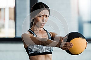 Sportswoman holding ball while exercising in gym