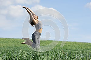 Sportswoman jumping happy in a green field