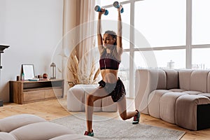 Sportswoman lunging forward with blue barbells at home
