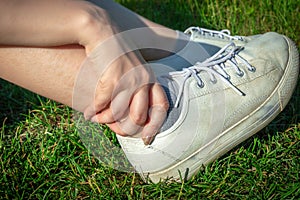 Sportswoman outdoors on grass touching painful twisted ankle. Athlete runner training accident