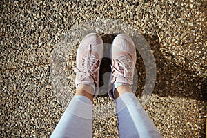 Sportswoman point of view. Legs and feet of female athlete in stylish running sports shoes, pink sneakers on the asphalt