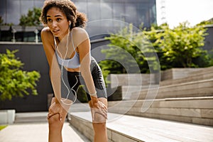 Sportswoman resting while working out outdoors at street