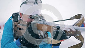 Sportswoman is shooting from her riffle during a biathlon race in a lying position