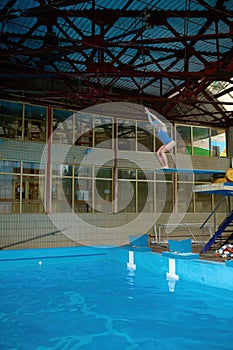 Sportswoman standing on diving board at public swimming pool ready to jump