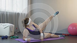 Sportswoman straightening legs lying on yoga mat at home, desire losing weight