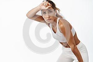 Sportswoman sweating, wiping forehead and taking break during workout, doing sport exercises, white background