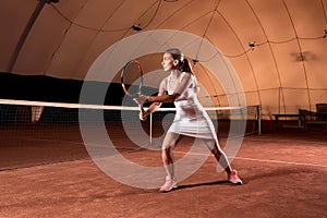 Sportswoman at the tennis court with racquet.