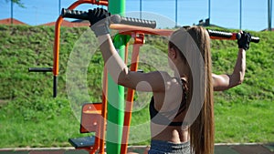 Sportswoman training back muscles using simulator outdoors.