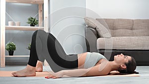 Sportswoman training at home on mat floor performing gluteal bridge exercise buttocks workout