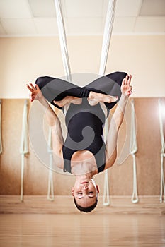 Sportswoman is trying loyus position in the antigravity yoga