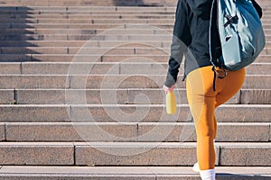 sportswoman walking up stairs with bottle in hand