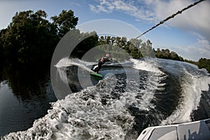 Sporty gue rides on wakesurf through the waves on water board photo