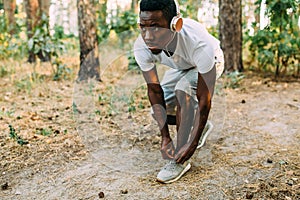 A sporty African American ties his shoelaces ready to run in the Park