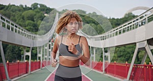 sporty african american woman looking at her sport bracelet on hand checking data on fitness tracker after jogging