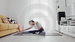 Slim sporty african american woman practicing yoga on a mat. Woman sits on fitness mat and stretches