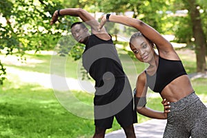 Sporty African Couple Doing Fitness Workout Together In Summer Park, Stretching Muscles