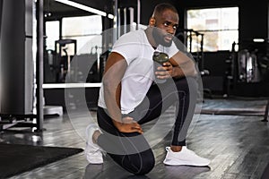 Sporty african man resting, having break drinking water after doing exercise.