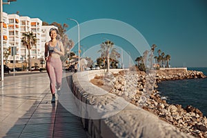 Sporty athletic lady actively running by the waterfront