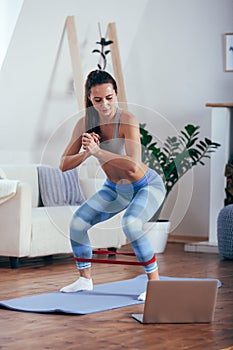 Sporty athletic woman exercising with rubber tape