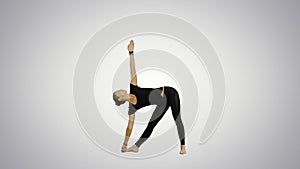 Sporty beautiful smiling young woman standing in Utthita Trikonasana, extended Triangle Pose on white background