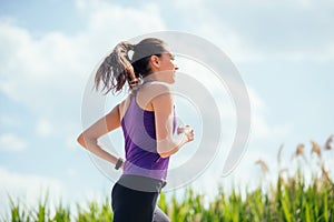 Sporty beautiful woman running in park on nature background. Sunny day, hard workout.