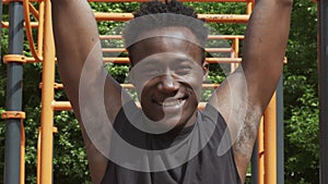 Sporty Black Guy Hanging On A Pull-Up Bar Exercising Outdoor