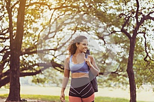Sporty black woman standing and holding yoga mat after break workout at park,Happy and smiling,Relaxing time,Positive thinking