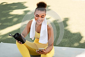 Sporty black woman in yellow sportswear listening to music