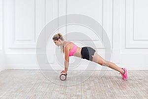 Sporty blonde woman using foam roller in gym to workout to remove the pain, stretching muscles.