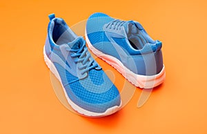 sporty blue sneakers pair on orange background, fitness