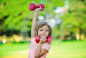 Sporty boy with dumbbells outdoor. Fitness kids, health and energy. Healthy kids lifestyle. Kid exercising with dumbbell