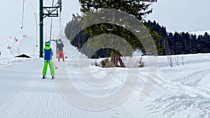 Sporty boy go up on t-bar ski lift at alpine resort